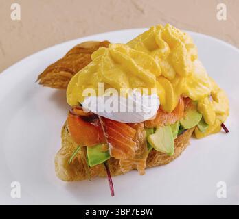 Essen, köstliches Croissant mit geräuchertem Lachs, Avocado und einem cremigen pochierten Ei Stockfoto
