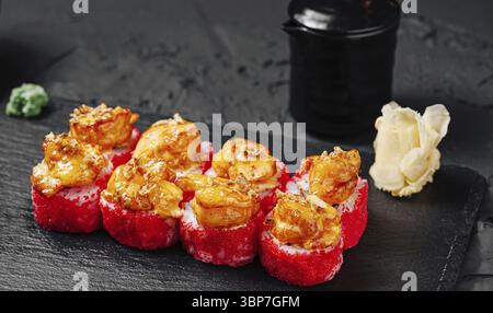 Essen, Eine wunderschön gestaltete Sushi-Platte zeigt lebendige rote Sushi-Brötchen mit gegrillten Garnelen. Wasabi und eingelegter Ingwer begleiten das Gericht Stockfoto