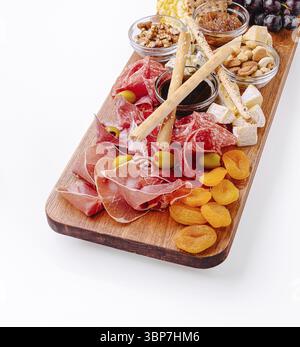 Essen, Eine schön gestaltete Wurstplatte zeigt eine Vielzahl von Wurstwaren, Käse, Obst, Nüssen und Dips, perfekt für die Unterhaltung der Gäste im Stockfoto
