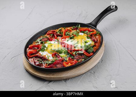 Essen, traditioneller Shakshuka mit Eiern, Tomaten und Paprika garniert mit Petersilie, serviert in einer gusseisernen Pfanne Stockfoto