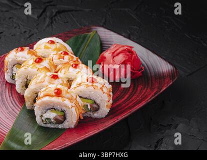 Essen, Ein Teller zeigt wunderschön arrangierte Sushi-Brötchen mit lebhaften Saucen, begleitet von einem Hügel eingelegtem Ingwer und einem Hauch Wasabi, s Stockfoto