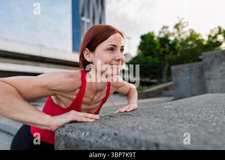 Frau, die in der Stadt arbeitet und im Freien Kraftübungen macht Stockfoto