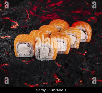 Essen, exquisite Lachsushi-Brötchen, kunstvoll präsentiert auf einem texturierten Holzkohlehintergrund Stockfoto