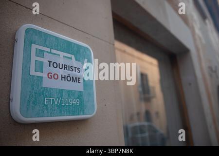 Santanyi, Spanien. Juli 2025. Ein Aufkleber mit der Aufschrift „Touris go höme“ ist über einem Schild angebracht, das auf eine Touristenunterkunft hinweist, an der Fassade eines Hauses in Santanyi auf Mallorca. In der kleinen Stadt Santanyi auf Mallorca haben unbekannte Menschen antideutsche Slogans auf Autos und Läden gesprüht. "Deutsche raus" oder "ausländische Käufer gehen in die Hölle" waren in roter Farbe auf Dutzenden von Läden deutscher Eigentümer und auf Autos mit ausländischen Nummernschildern geschrieben. Quelle: Clara Margais/dpa/Alamy Live News Stockfoto