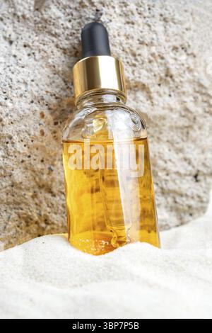 Nicht gebrandete kosmetische Tropfflasche mit feuchtigkeitsspendender Flüssigkeit. Vitamin C-Serum in der Pipettenflasche auf Sand- und Steingrund. Modup-Style. Schönheitskitten Stockfoto