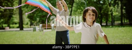 Junge mit Dad fliegendem Kite zusammen im Sunny Park Stockfoto