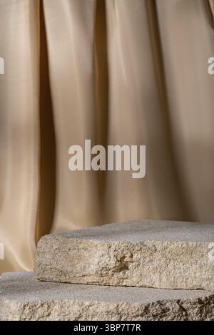 Beige Natursteine Podium auf beigem textilen Vorhang Hintergrund, Plattform für Produktpräsentation. Leer für Modelldesign. Vorderansicht. Kopierbereich Stockfoto