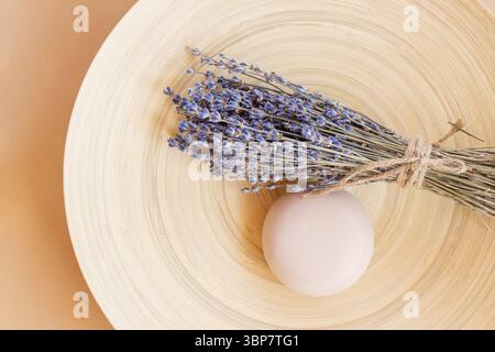 Handgemachte Lavendelseife. Ein Stück Naturseife in Kugelform mit getrockneten Lavendelblüten auf einem Holzteller. Bio-Kosmetik für Hautpflege und Spa Stockfoto