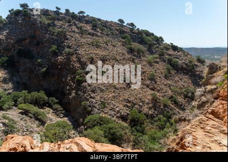 Besucher bewundern das zerklüftete Gelände rund um die Milatos-Höhle auf Kreta unter klarem blauen Himmel. Stockfoto