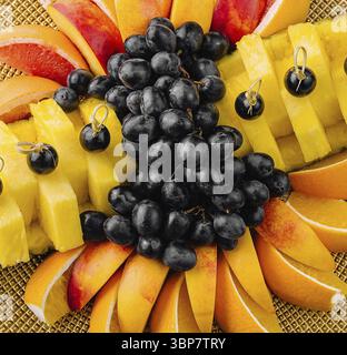 Speisen, bunte Auswahl an frischem Obst, einschließlich Trauben, Mango und Papaya auf einem runden Korbteller Stockfoto