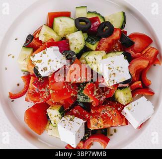 Essen, Blick von oben auf einen bunten griechischen Salat, der auf einem weißen Teller serviert wird Stockfoto