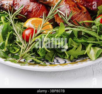 Essen, köstliches gebratenes Hähnchen serviert mit Rucola-Salat, Kirschtomaten und Orangenscheiben Stockfoto