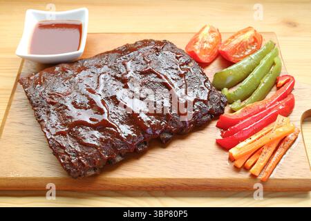 Köstliche BBQ Schweinerippchen mit gegrilltem Gemüse auf einem Schneidebrett Stockfoto