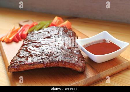 Köstliche BBQ Schweinerippchen mit gegrilltem Gemüse auf einem Schneidebrett Stockfoto