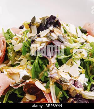 Essen, Ein lebendiger Salat mit einer Mischung aus frischem Gemüse, Mandelscheiben und Kürbiskernen, garniert mit einem leichten Dressing. Ein köstliches und nahrhaftes Opti Stockfoto