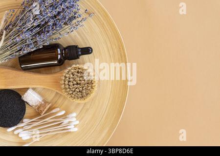 Flatlay Komposition mit Lavendelblüten und Naturkosmetikprodukten. Bio-WELLNESS-Kosmetik. Gesichtsserum, ätherisches Öl, massierenden Gesichtsbürste, Schwamm Stockfoto