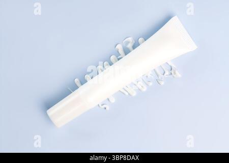 Creme-Tube auf blauem Hintergrund. Leere Kunststoffverpackung für Kosmetikprodukte. Weiße Lotion ohne Marke, Balsam, Handcreme, Zahnpasta Mockup mit Creme Stockfoto