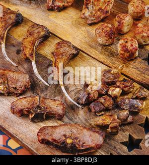 Essen, köstliche Lammkoteletts und Fleischbällchen serviert auf einer rustikalen Holzplatte mit einer Vielzahl von gegrilltem Fleisch Stockfoto