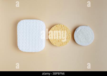 Set aus verschiedenen Schwämmen für das Gesicht. Reinigende und peelnde Schwämme auf beigem Hintergrund. Hautpflegekonzept Stockfoto