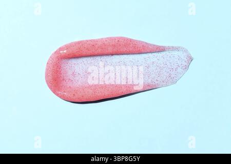 Schrubben auf blauem Hintergrund. Kosmetisches Peeling mit Textur für Gesicht und Körper mit roten abrasiven Partikeln. Peeling-Körper polieren Textur als kosmetische gomm Stockfoto