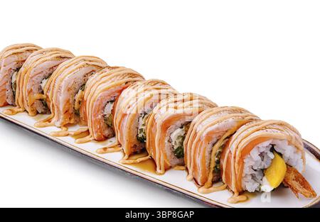 Essen, frisch zubereitete Sushi-Brötchen, ordentlich auf einem weißen Teller, mit Sauce besprüht. Die Brötchen enthalten verschiedene Zutaten und werden garniert, so dass sie hergestellt werden Stockfoto