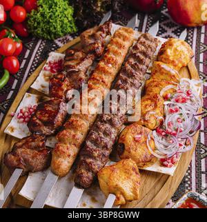 Essen, köstliche traditionelle Grillspießplatte mit gegrilltem Fleisch, verschiedenen Gemüsesorten und scharfer Sauce auf einem Holzbrett für eine Gourmet-Küche Stockfoto