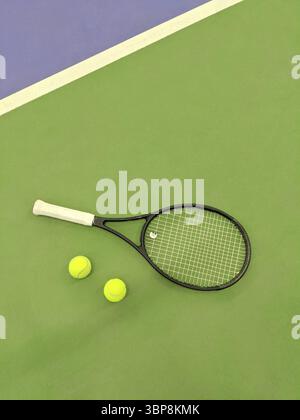 Blick von oben auf Tennisschläger und zwei Bälle auf dem grünen Tennisplatz Stockfoto