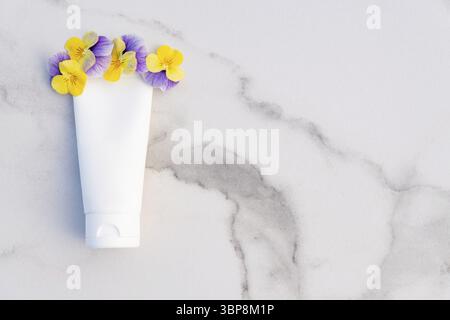 Weiße Squeeze-Flasche kosmetische Creme Rohr und Stiefmütterchen Blumen auf Marmor Hintergrund mit Kopie Raum. Draufsicht. Brandlotion, Balsam, Handcreme, feucht Stockfoto
