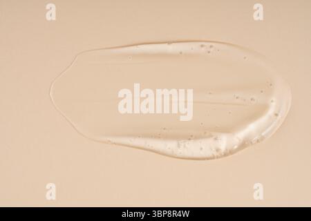Gepresste kosmetische klare Creme Gel Textur isoliert auf beigem Hintergrund. Schließen Sie den transparenten Serumtropfenausstrich Stockfoto
