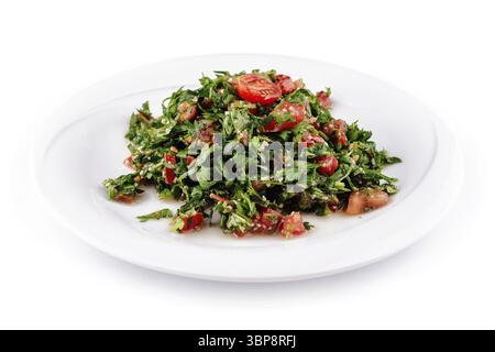 Essen, frisch zubereiteter Tabbouleh-Salat, bestehend aus Petersilie, Tomaten und anderen frischen Zutaten, auf einem weißen Teller Stockfoto