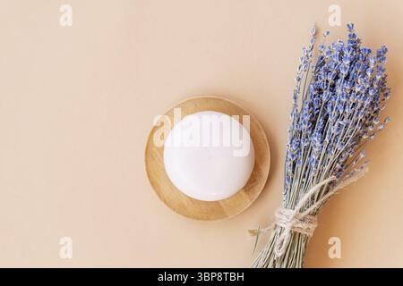Handgemachte Lavendelseife. Ein Stück Naturseife in Kugelform mit getrockneten Lavendelblüten auf einem Holzteller. Bio-Kosmetik für Hautpflege und Spa Stockfoto