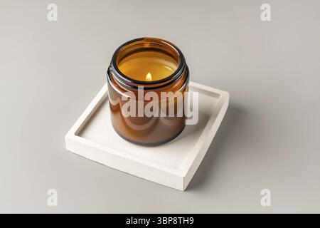 Handgemachte Kerze aus Paraffin und Sojawachs im Glas auf Betonschale. Kerzenherstellung. Minimalismus Stockfoto