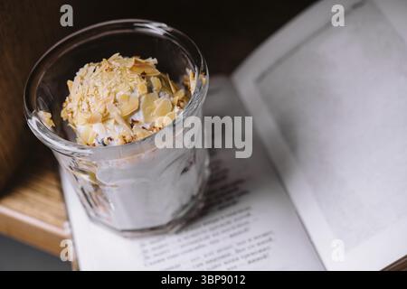 Essen, Eisbecher mit Mandeln und Buch Stockfoto