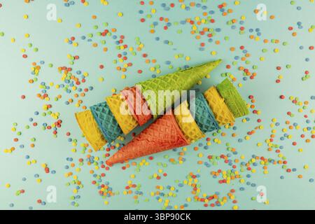 Set aus verschiedenen hellen bunten Eis Waffelkonen auf blau Hintergrund mit verstreuten Konfetti Zucker bestreut Stockfoto