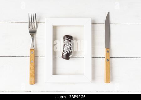 Gesundes Ernährungs- und Ernährungskonzept. Kleiner Nachtisch in einem Bilderrahmen serviert mit Gabel und Messer auf weißem Tisch Stockfoto