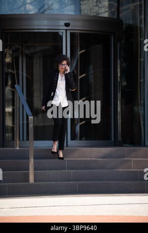 Geschäftsfrau telefoniert am Telefon vor dem Bürogebäude Stockfoto