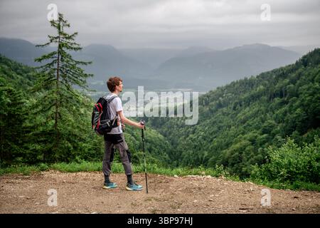 Männlicher Wanderer mit Trekkingstöcken, die den Blick auf die Berge in Österreich bewundern Stockfoto