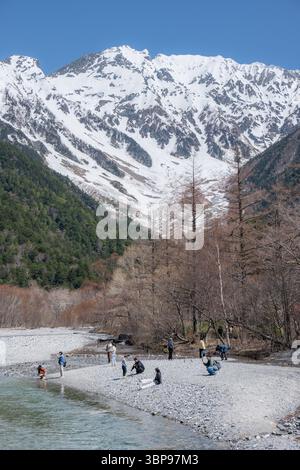 Touristen am Flussufer mit Bergblick in Kamikochi Stockfoto