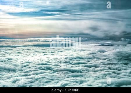 Luftaufnahme über der dichten Schicht flauschiger weißer Cumulus-Wolken, die sich bis zum Horizont unter dem weiten Himmel erstrecken. Wolkenmeer, faszinierender Himmel mit schroffen Zirren Stockfoto