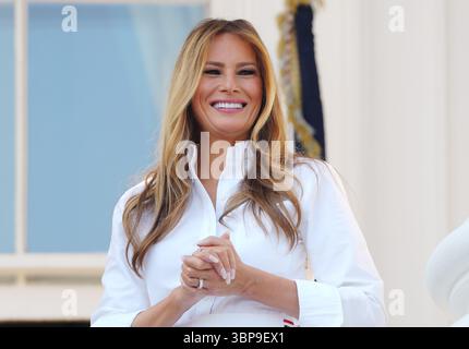 Washington, Usa. Juli 2025. First Lady Melania Trump lächelt, während Präsident Donald Trump am 4. Juli 2025 während eines Familienpicknicks im Weißen Haus in Washington DC mit Militärpersonal spricht. Foto: Bonnie Cash/Pool/SIPA USA Credit: SIPA USA/Alamy Live News Stockfoto