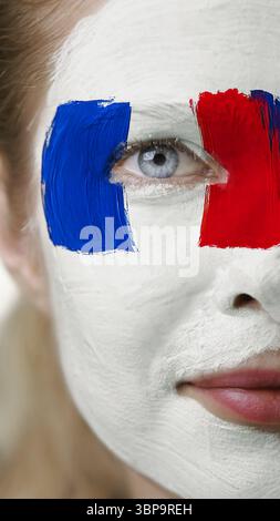 Das Gesicht ist mit französischen Flaggenfarben gemalt, die den Nationalstolz und die persönliche Identität widerspiegeln Stockfoto