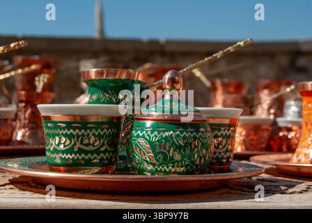 Traditionelle türkische Kupferkaffeekanne mit grüner Patina und passenden Tassen, bereit für die Zubereitung von reichhaltigem türkischem Kaffee. Stockfoto