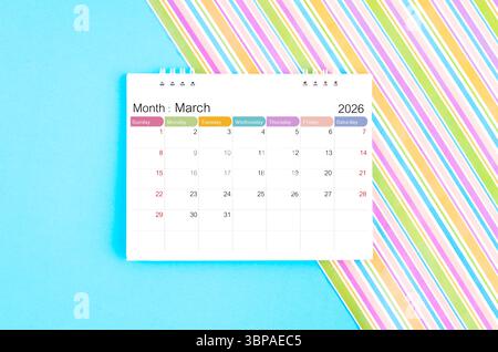 Tischkalender März 2026 auf blauem und Regenbogenhintergrund. Stockfoto