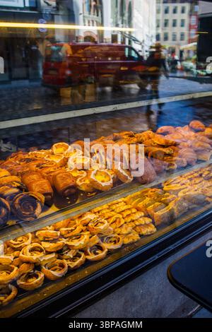 Dänisches Gebäck: Viele verschiedene süße Brötchen werden in der Bäckerei durch das Fenster von der Straße aus hergestellt Stockfoto