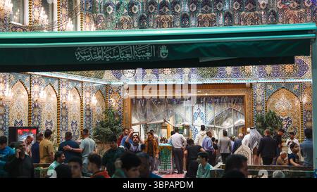 Besucher interagieren am Imam Hussein-Schrein in Karbala, Irak, während die Nacht hereinbricht und Gebete geboten werden. Stockfoto
