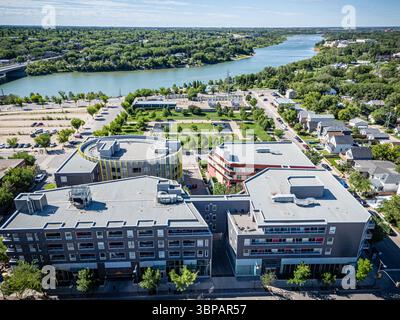 Blick auf die Stadt mit einem Fluss, der durch sie fließt. Die Gebäude sind hoch und es stehen viele Autos auf dem Parkplatz Stockfoto
