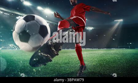 Der Fußballspieler schlägt den Ball auf dem 3D-Feld unter Stadionlichtern in Nahaufnahme Stockfoto