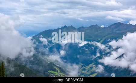 Gewitter Wolken über den Bergen. Grüne Wiesen, verstreute Siedlungen und dunkle Wälder unter beeindruckenden und interessanten Wolken. Stockfoto