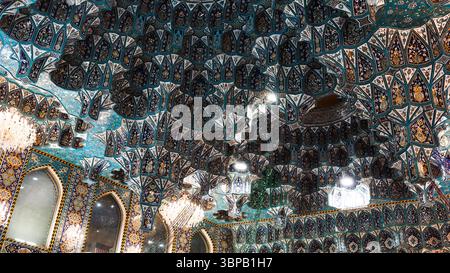 Besucher bewundern die atemberaubende Handwerkskunst eines historischen Gebäudes in Karbala, Irak, mit lebendigen Farben und detaillierten Mustern. Stockfoto