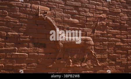 Ein detailliertes Relief einer Giraffe ist in eine Backsteinmauer in Babylon, Irak, gemeißelt und zeigt antike Kunst und Kultur. Stockfoto